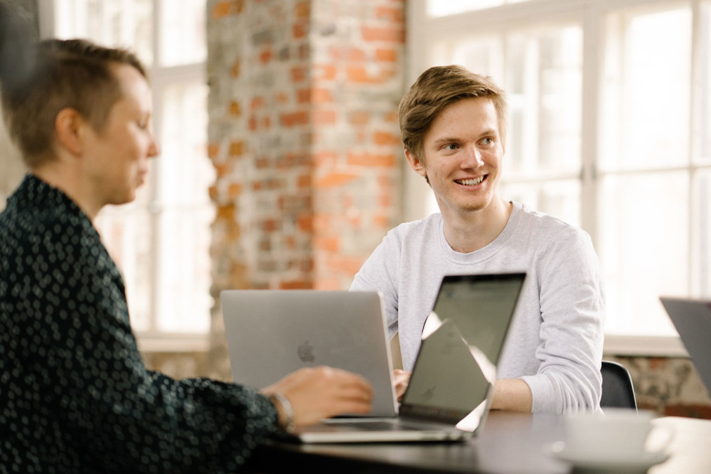 Mies istuu tietokoneen ääressä hymyilevä
